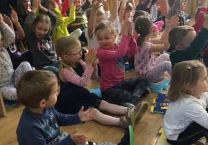 Na zdjęciu znajdują się dzieci klaszczące w rytm słyszanej muzyki