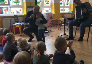 Na zdjęciu jest pan Maciej Goździela, który śpiewa i przytula chłopca