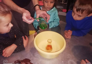Zdjęcie przedstawia dzieci robiące experyment o magicznym wulkanie.