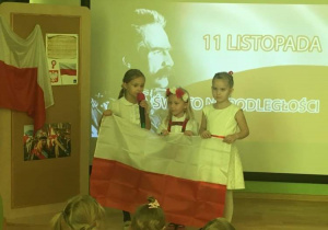 Na zdjęciu znajdują się śpiewające dziewczynki z flagą Polski.