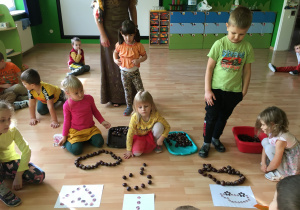 Na zdjęciu widać dzieci układające kasztanowe wzory