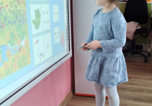 Dziewczynka rozwiązująca zadania na tablicy multimedialnej