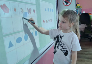 Dziewczynka rozwiązująca zadania na tablicy multimedialnej