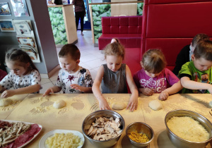 Dzieci w trakcie pracy nad własną pizzą
