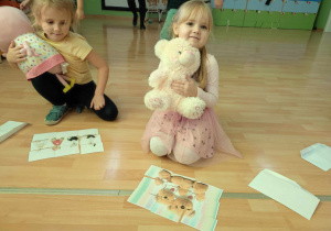 Na zdjęciu znajdują się dzieci układające puzzle z misiem.