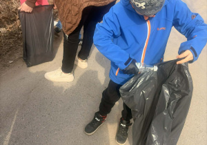 Chłopiec wrzucający śmieci do worka