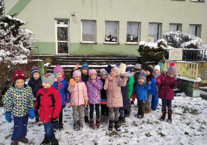 Dzieci stojące na tle przedszkolnego budynku